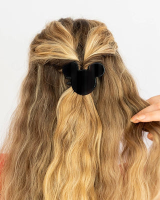 Person with long, wavy hair using a black hair clip on a white background