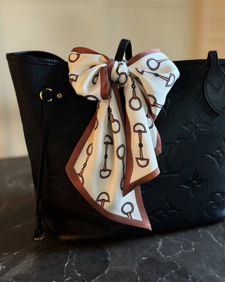Black handbag with a decorative scarf on a marble surface