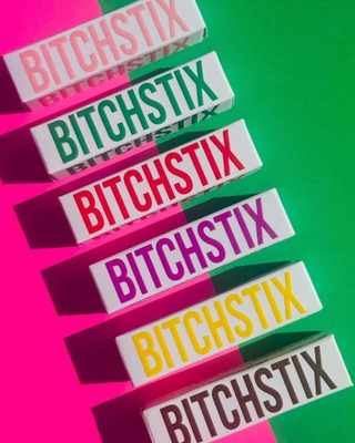 6 bitchstix lip balm boxes on neon pink and green background