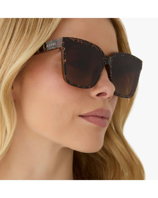 Close-up of a woman wearing sunglasses with a leopard print frame.