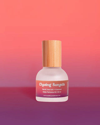 Roller perfume oil bottle with wooden cap on a gradient pink and purple background