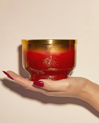 Hand holding a red and gold jar apple cider candle