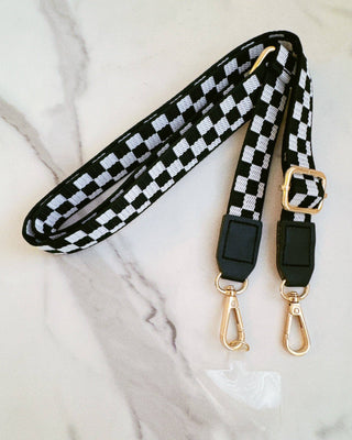 Black and white checkered strap with gold hardware on a marble surface