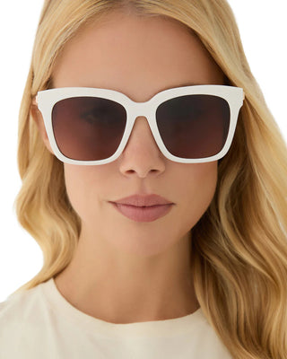 Woman wearing white sunglasses with a neutral background