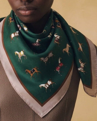 Person wearing a green scarf with horse pattern on a beige background