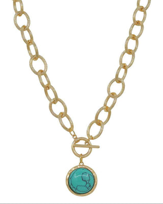 A gold chain necklace with a toggle clasp and a round turquoise pendant featuring a gold crescent moon design, shown against a plain white background.