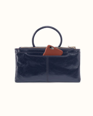A navy blue leather clutch bag with a circular top handle and a brown leather tag, shown against a plain off-white background.