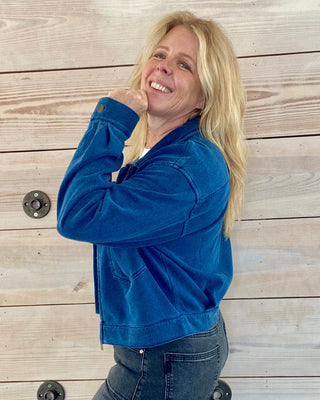 Woman wearing a blue jacket standing against a wooden background