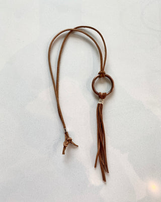 Brown leather necklace with tassel on a light gray background