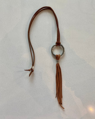 Brown leather keychain with a tassel on a light gray background