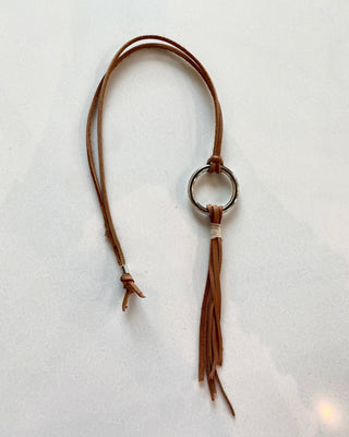 Brown leather necklace with a tassel on a light gray background