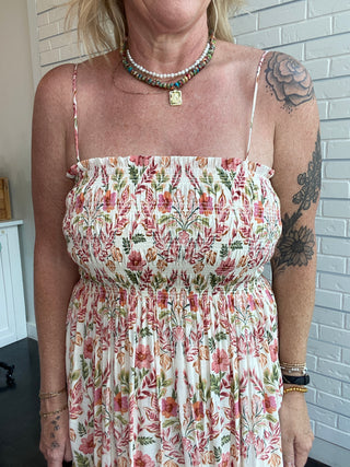 Person wearing a floral dress with a white brick wall background