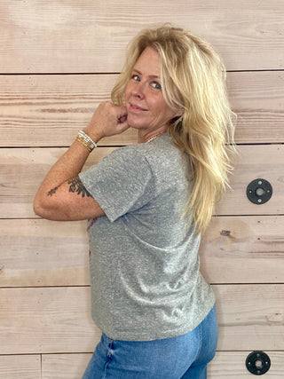 Woman wearing a silver glittery top and blue jeans against a wooden background
