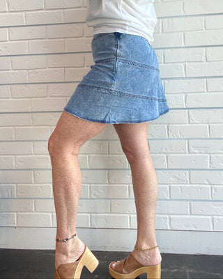 Person wearing a white top and blue denim skirt lying on a tiled floor.