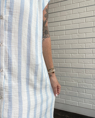 Person wearing a striped shirt with a gray tiled wall background