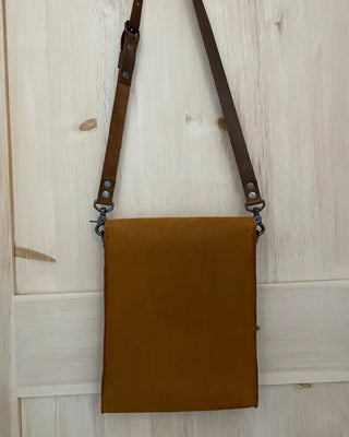 Brown leather bag with strap on a light wooden floor
