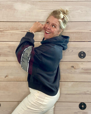 Person wearing a dark hoodie with a patterned design on a wooden background