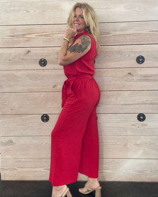 Person wearing a red jumpsuit standing on a wooden floor.