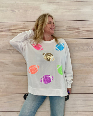 Woman wearing a light gray sweatshirt with colorful graphic designs against a wooden background