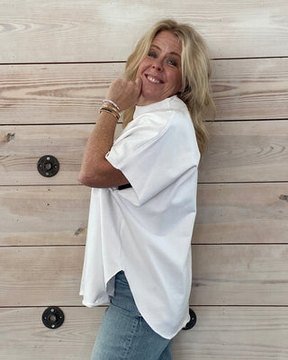 Person wearing a white shirt and blue jeans on a wooden floor