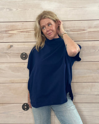 Person wearing a navy blue top and light blue jeans on a wooden floor