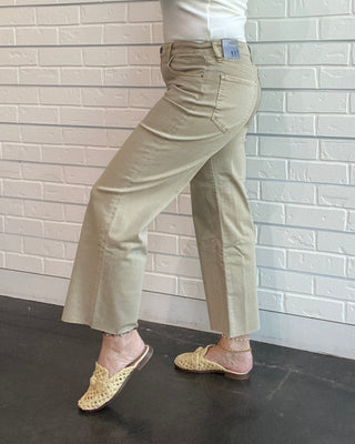 Person wearing denim overalls standing against a wooden wall.