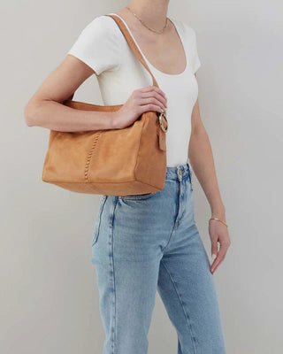 Person holding a brown leather handbag against a plain background