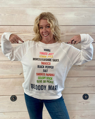 Person wearing a white sweatshirt with text design against a wooden background