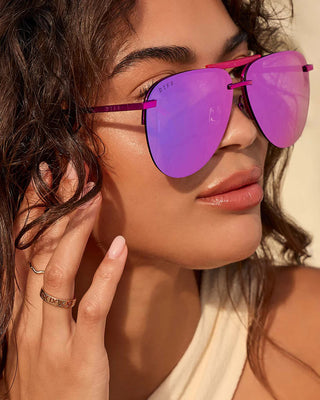 Woman wearing pink sunglasses with a neutral background
