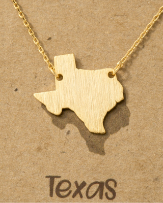 Gold necklace with Texas-shaped pendant on a brown background