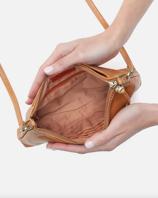 Brown leather handbag held by a person against a white background