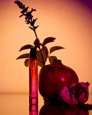 Perfume bottle with a pomegranate and lavender plant on a warm-toned background