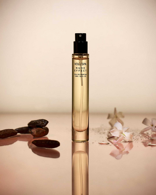 VOLUSPA perfume bottle with 'Nude Effect' on a reflective surface with decorative elements.