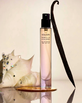 Voluspa Vanilla Visions candle and vanilla pod on a reflective surface with a neutral background