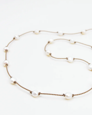 A white pearl necklace with brown rope-like strings and a sliding knot closure.