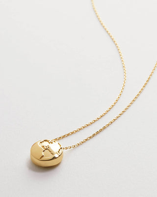 A gold chain necklace with a small, polished gold pendant featuring a stylized face, displayed on a clean, light gray background.