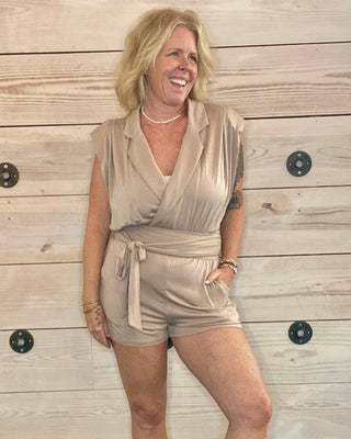 Woman in beige outfit standing against a wooden wall