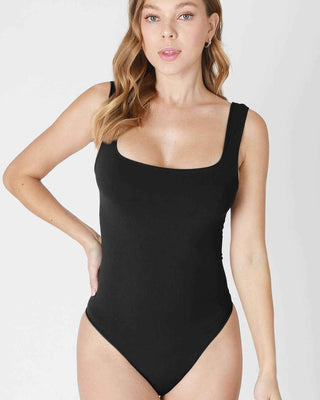 Woman wearing a black bodysuit against a white background