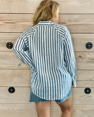 Person wearing a blue and white striped shirt against a wooden wall.
