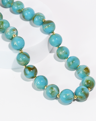 Turquoise beaded necklace with gold accents on a white background