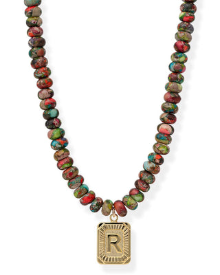 Necklace with multicolored beads and a gold pendant with 'R' on a white background