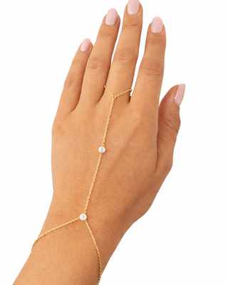 Gold hand chain with cz stones on a hand against a white background