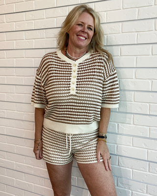 Woman wearing a matching striped outfit against a light brick wall.