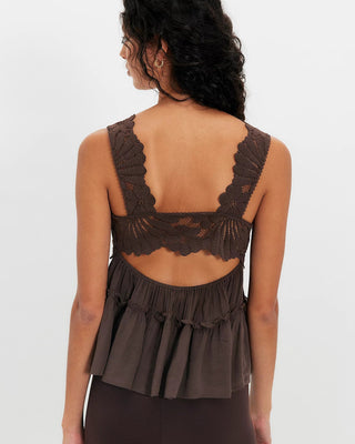 Woman wearing a brown lace top with a plain background