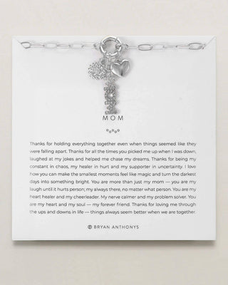 Silver bracelet with heart charm on a white card with text, on a light gray background