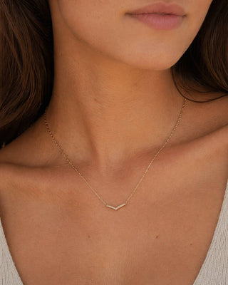 Close-up of a person wearing a delicate gold necklace with a small pendant.