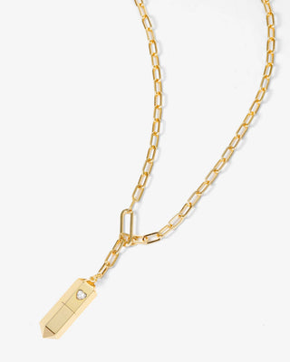 A gold chain necklace featuring a rectangular pendant with a pointed tip and a small clear rhinestone, displayed on a clean white background.