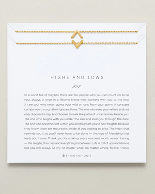 A white square card with a gold envelope-style border and a gold heart-shaped clasp at the top, featuring the text 'HIGHS AND LOWS' and a short poem by Bryan Anthony. The card is photographed on a light gray background.