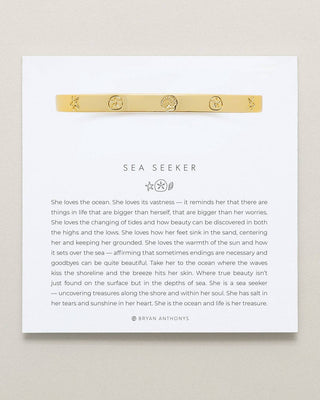 Gold bracelet on a white card with text on a beige background