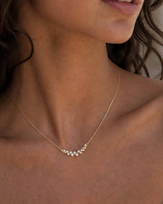 Close-up of a woman wearing a delicate gold necklace with small stones.